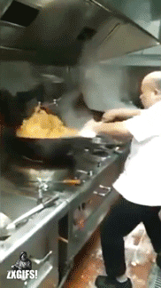 Man with large wok making a large party serving stir fry in a restaurant